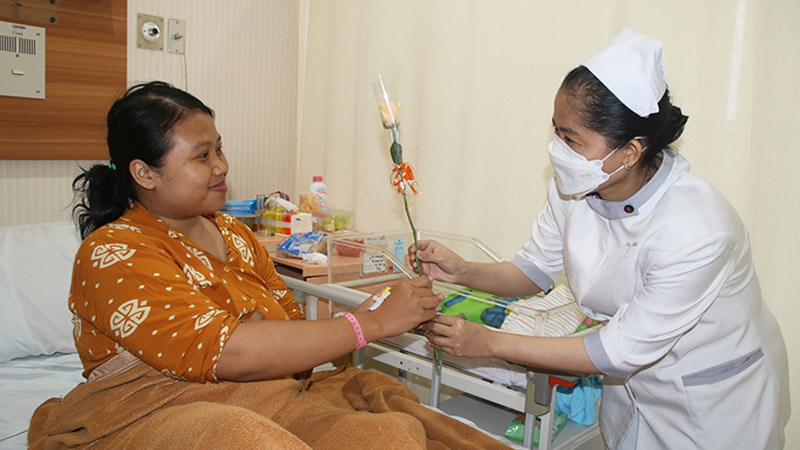 seorang bidan memberikan bunga kepada seorang ibu